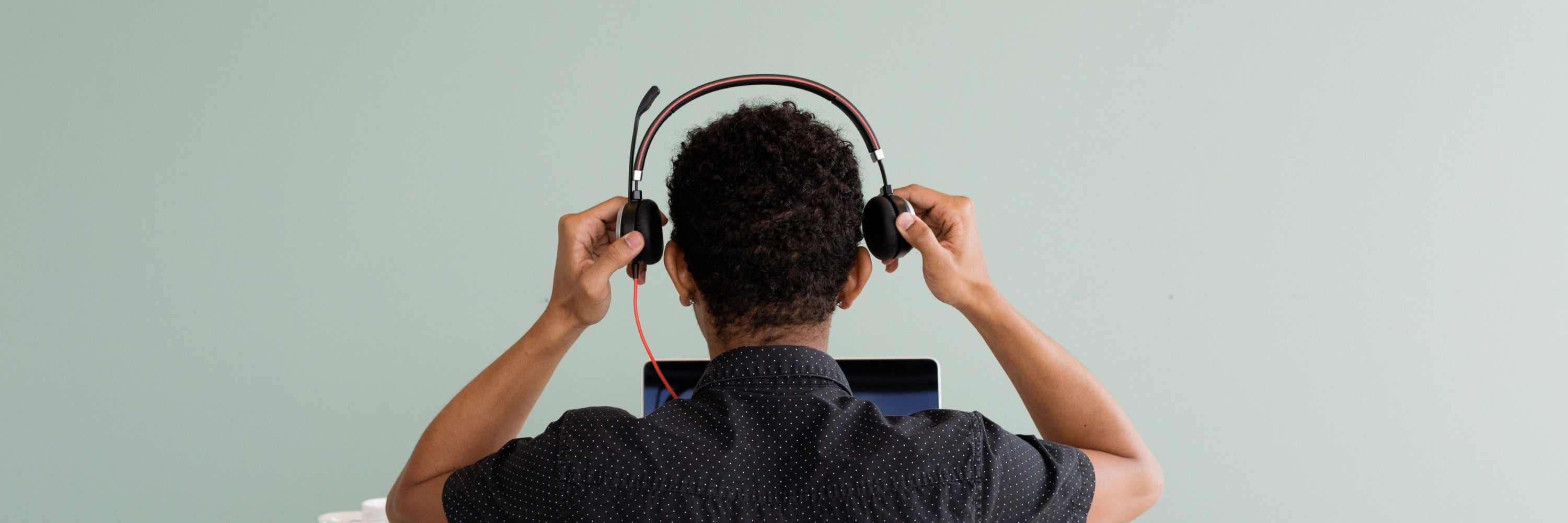 Customer adjusting headphones while using a NeoDesk product, representing NeoDesk’s commitment to quality and warranty support.