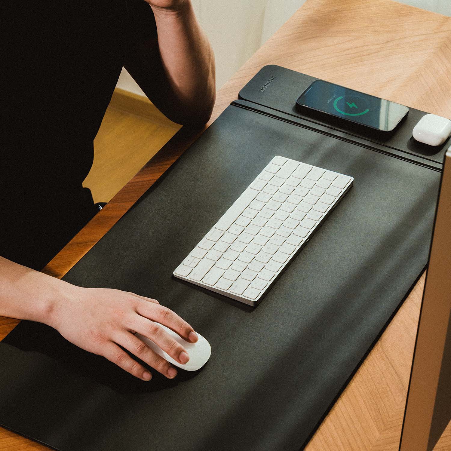 NeoDesk wireless charging desk mat in a professional office setting with a sleek black design, keyboard, and seamless charging.