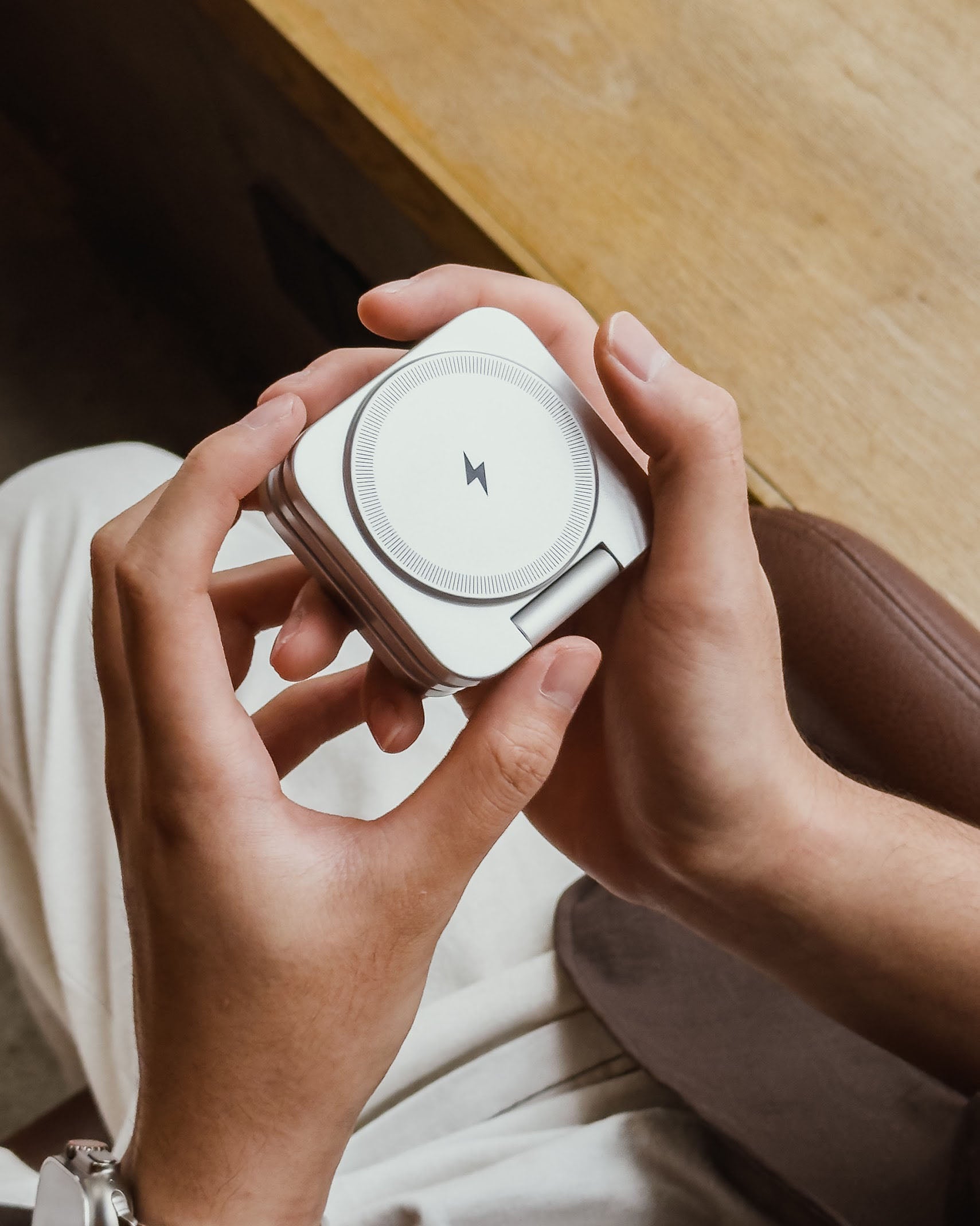 Hands holding the NeoDesk Portable 3-in-1 Wireless Charger, showcasing its compact design and premium craftsmanship.